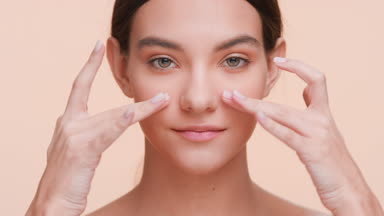 Beauty model softly touches her face under eyes with her fingers