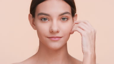 Young woman softly touches her face with her hands