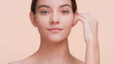 Young woman touches her face with hand and smiles