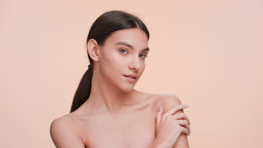 Young woman strokes her shoulder and looks at the camera.