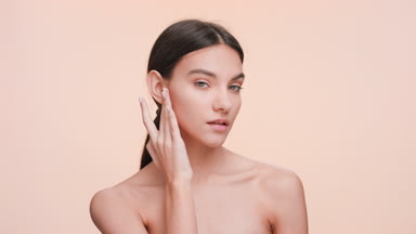 Young woman touch and strokes her jawline and look at the camera