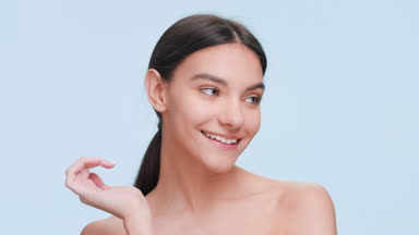 Beauty model touches her cheek with fingers and smiles