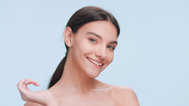 Beauty model strokes fast her cheek with fingers and smiles