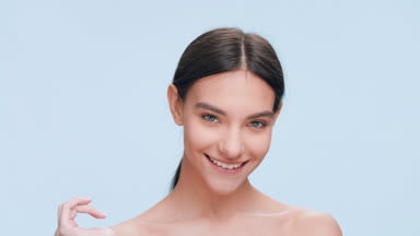 Beauty model strokes her cheek with fingers and smiles