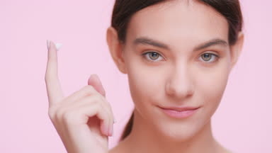 Young woman shows a drop of a cream on her finger