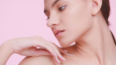 Beauty model strokes her shoulder, looks at the camera and smiles