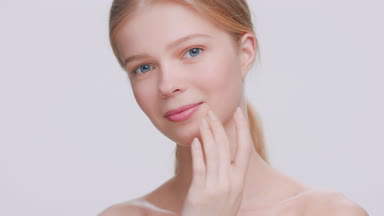 Woman runs her fingers along the jawline and looks at the camera