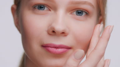 Beauty model softly touches her face and looks at the camera