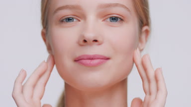 Young woman touches face with fingers from forehead to jawlines