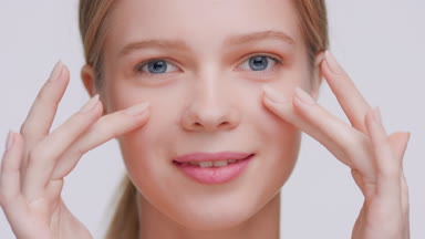 Blonde beauty model touches her face with hands