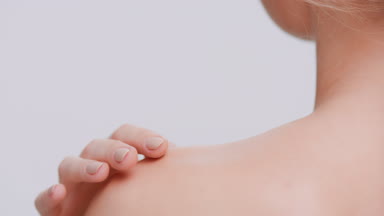 Woman softly strokes her skin from the neck to the shoulder