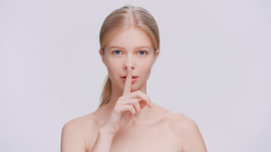 Beauty model looks at the camera and makes a silent gesture
