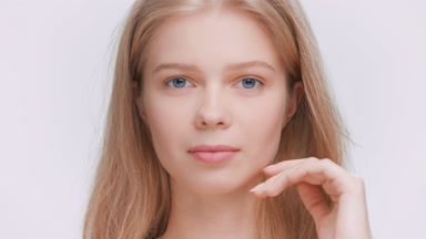 Woman turn her face and look at the camera touching her face