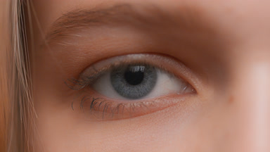 Macro shot of woman opens her eye and looks at the camera