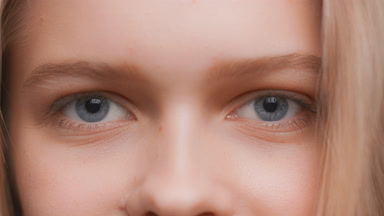 Young woman opens her eyes and looks at the camera