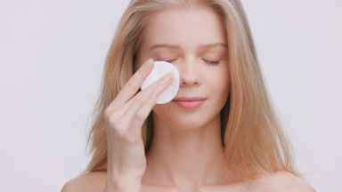Young woman applies skin care product using a cotton pad