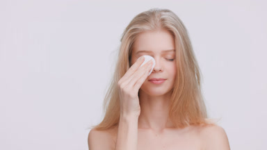 Beauty model applies skin care product using a cotton pad
