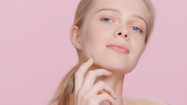 Blonde woman touches her face with hands