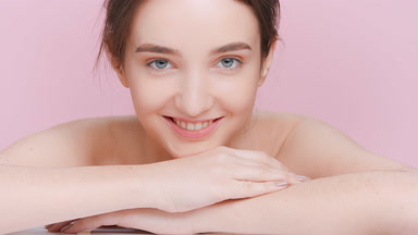 Young woman lays her chin on her hands and looks at the camera