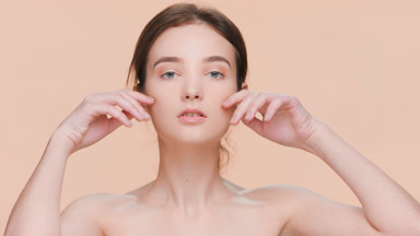 Young brunette beauty model gently touches her face with hands