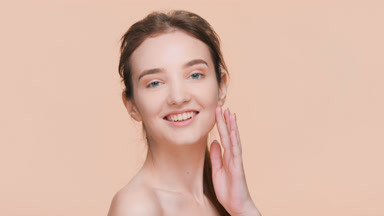 Young woman turns to the camera, touch her face and smiles