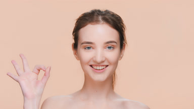 Brunette woman looks at the camera and makes an ok hand gesture