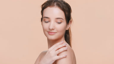 Young woman gently touches her shoulder and looks at the camera