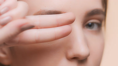 Girl looks through her v-gesture fingers at the camera and smiles
