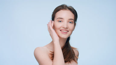 Young woman turns to the camera and gently touches her soft skin