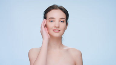 Young woman softly touches her face looks at a camera and smiles