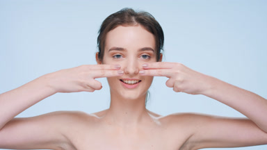 Young woman demonstrates skin elasticity and looks at the camera