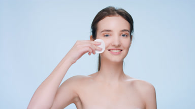 Girl demonstrates usage of skincare product using a cotton pad