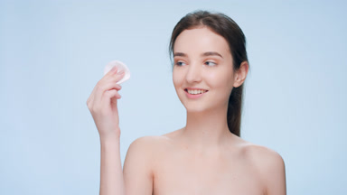 Young woman uses a cotton pad to clean her face