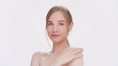 Young woman slides her hand down a shoulder and looks at camera