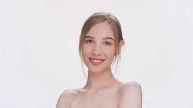 Young light-haired woman gently touches her face and smiles