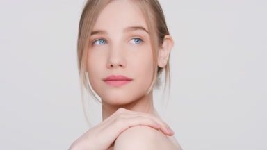 Young woman touches her shoulder turns and looks at the camera