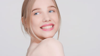 Young woman puts her chin at the shoulder, and smiles widely
