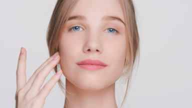 Young woman touches her face and posing for skincare product ads
