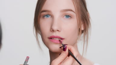 Make-up artist making up beauty model's lips