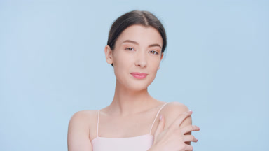 Young woman touches her shoulder, turns and looks at camera