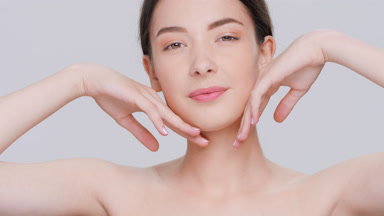 Brunette woman touches her face with back side of her hands