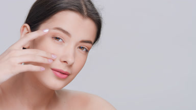 Sensual woman touches her face with pleasure and looks at camera