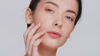 Woman touches face sliding fingers from cheek down to her chin