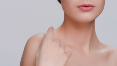 Woman touches her skin runs hand along clavicles to the shoulder
