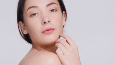 Young woman look at camera through her shoulder and touches skin