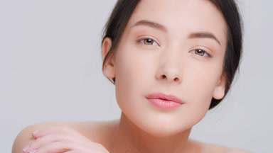 Dark-haired woman with perfect skin lays her head on her arms