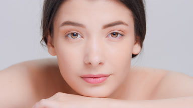 Young woman lays her chin on her hands and looks at camera