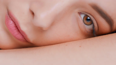 Young woman slowly lays her face on her forearm, looks at camera