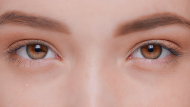 Macro shot of young woman opens her eyes and looks at camera