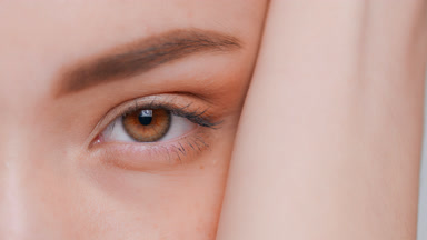 Macro shot of young woman opens her eye and looks at camera